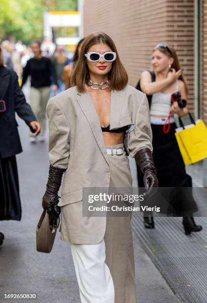 Guest wears asymmetric grey blazer, brown gloves, white pants outside Fendi during the Milan Fashion Week - Womenswear Spring/Summer 2024 on...