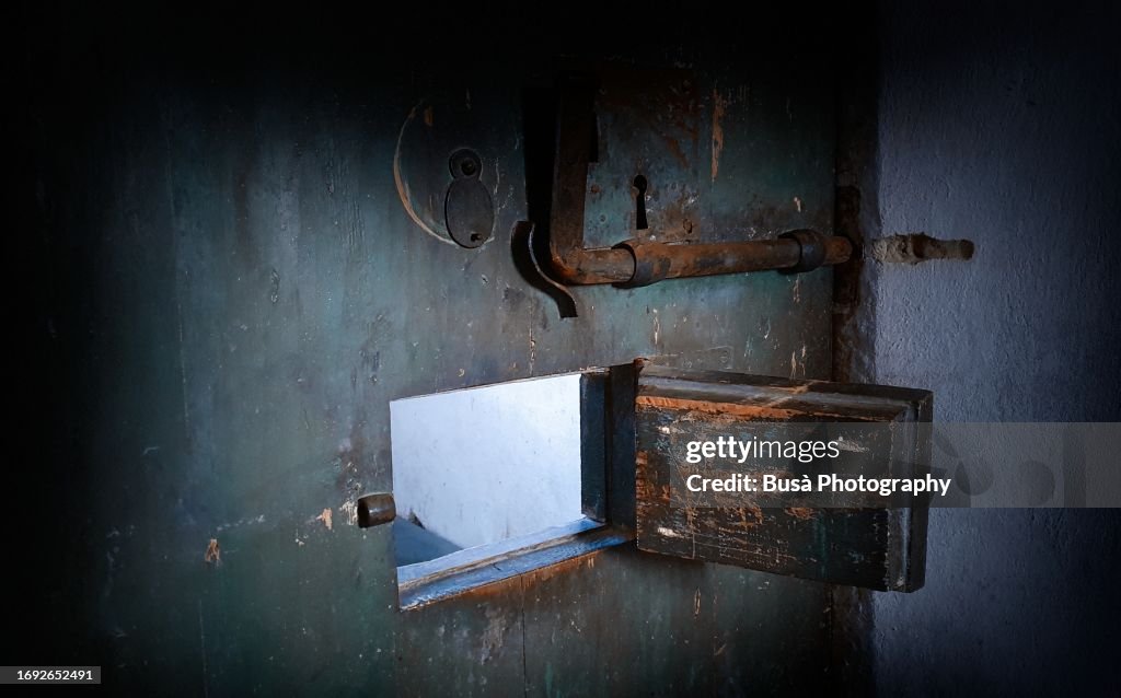 Rusty deadbolt lock latches and hole on ancient wooden door