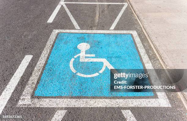 handicapped parking sign painted on the street in blue color. - simbolo internazionale di accesso foto e immagini stock
