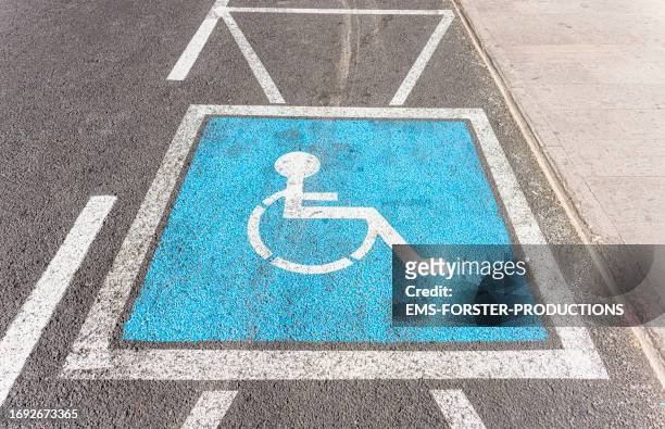 handicapped parking sign painted on the street in blue color. - sia - fotografias e filmes do acervo