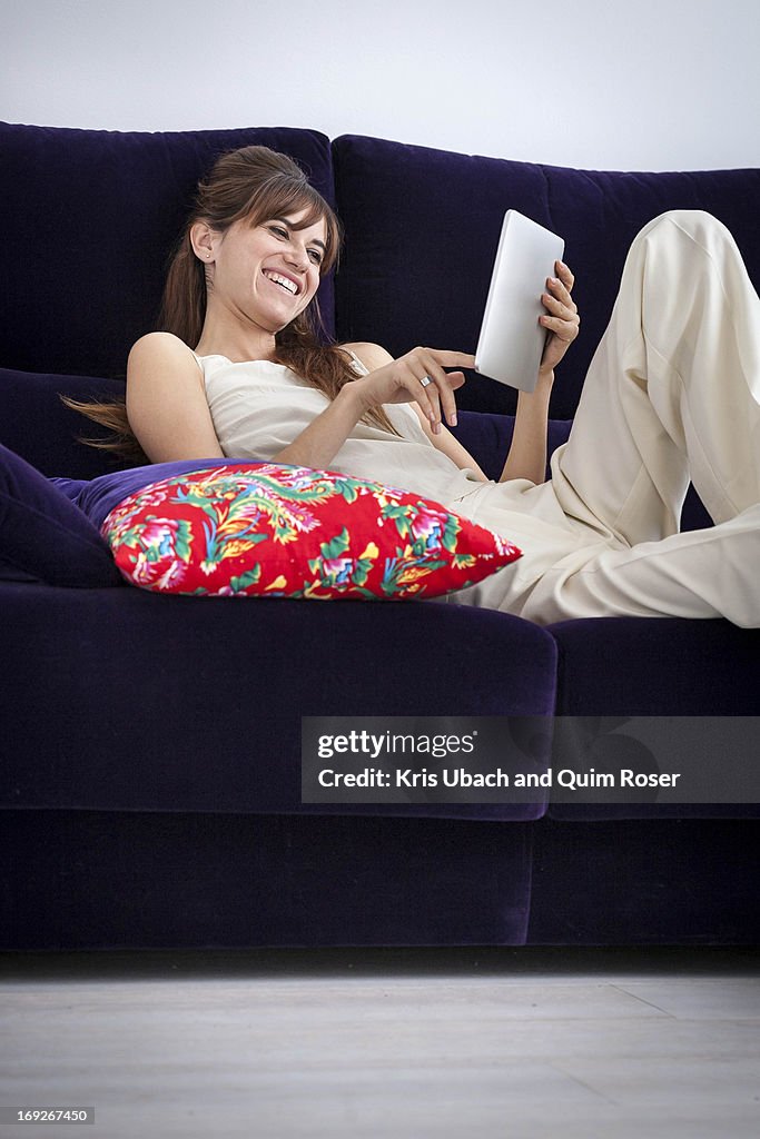 Woman using tablet computer on sofa