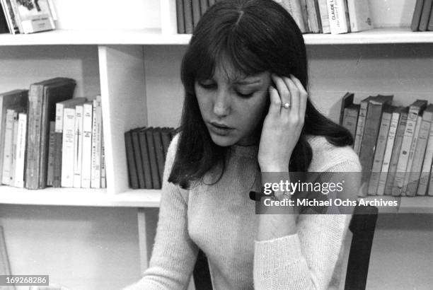 Anne Wiazemsky sitting in front of bookshelf in classroom in scene from the film 'La Chinoise', 1967.