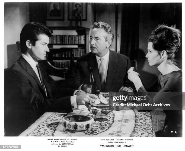 George Chakiris and Susan Strasberg looking at each other across the table in a scene from the film 'McGuire, Go Home!', 1964.