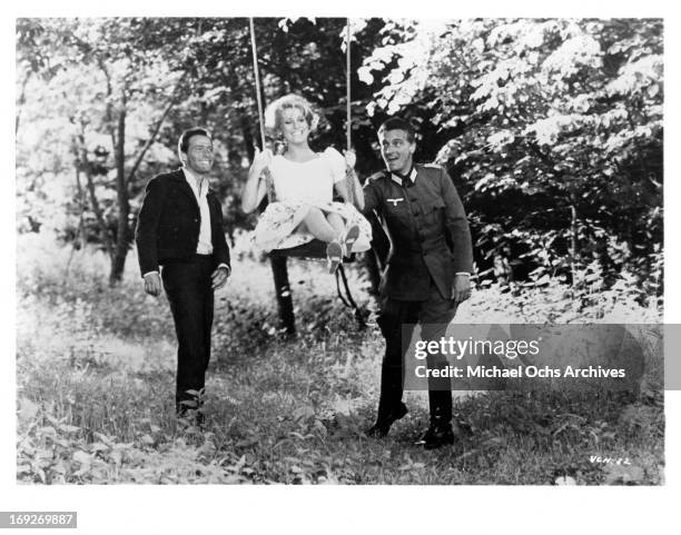 Henri Garcin and Carlos Thompson pushing Catherine Deneuve on a swing in a scene from the film 'A Matter Of Resistance', 1966.