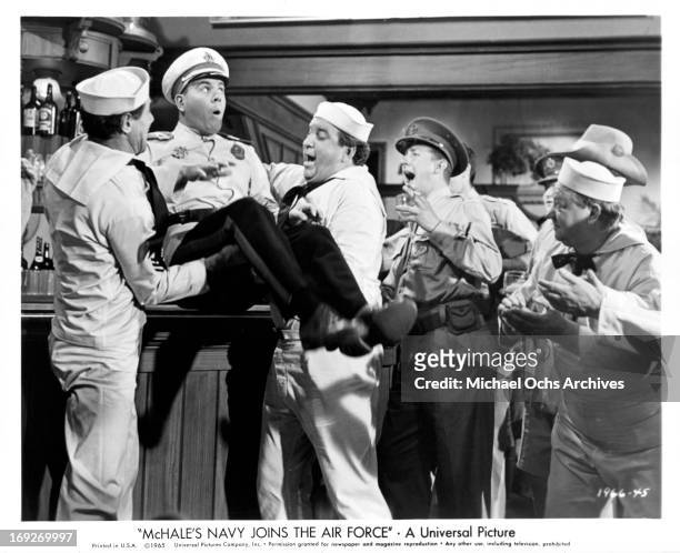 Tim Conway is hoisted onto an Australian bar by his newly-found 'comrades' in a scene from the film 'McHale's Navy Joins The Air Force', 1965.