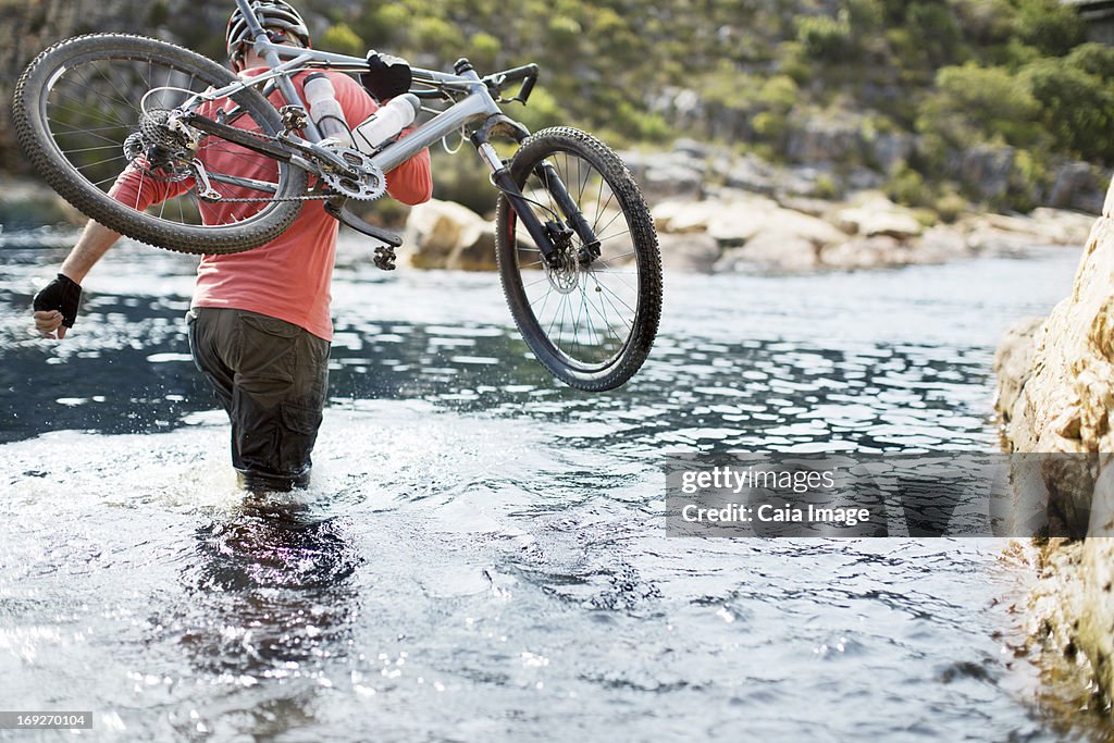 Uomo portare mountain bike nel fiume