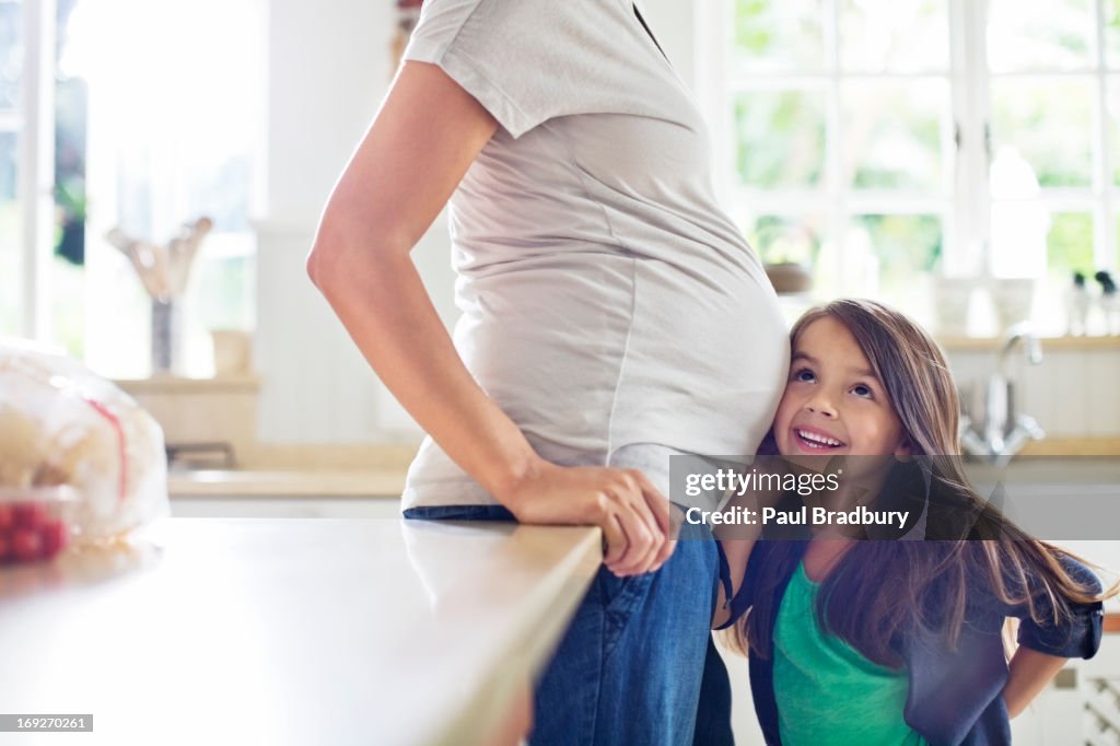 Girl listening to pregnant motherís belly