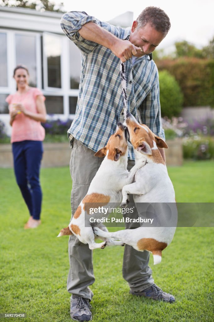 Hombre jugando con perros en el jardín