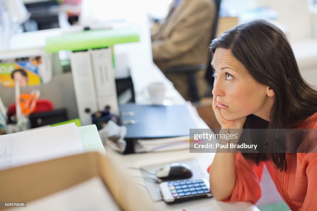 Businesswoman resting chin in hand on desk