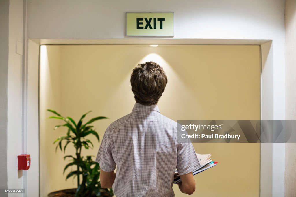 Businessman examining ëexití sign in office
