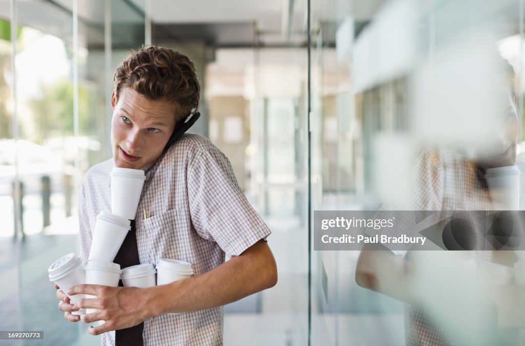 Businessman balancing coffees in office