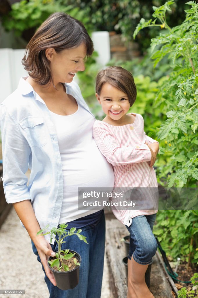 Girl and pregnant mother gardening together