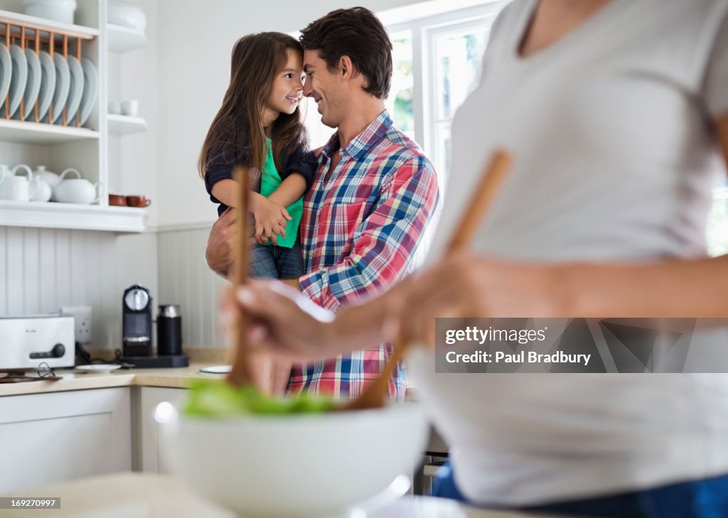 Father and daughter touching noses in kitchen