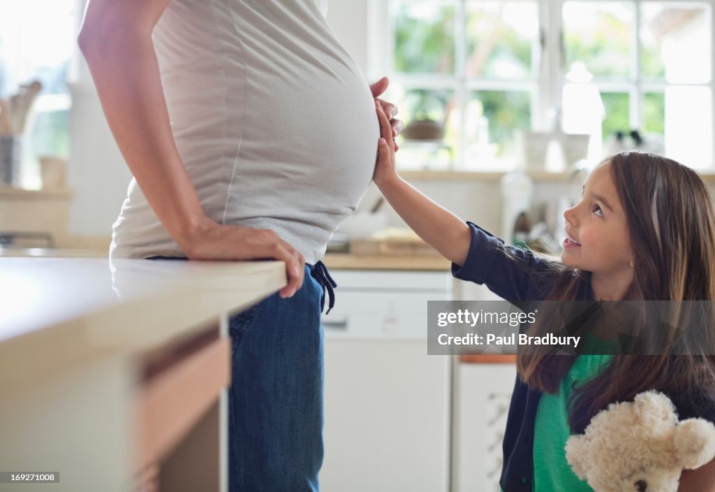 Girl holding pregnant motherís belly