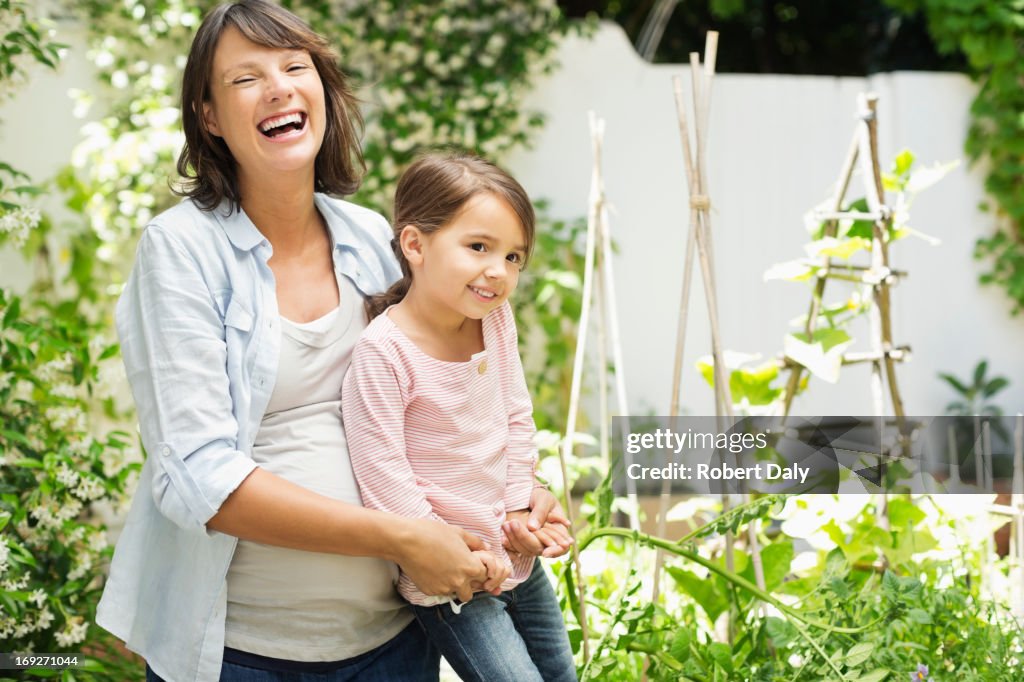 Pregnant mother and daughter gardening together
