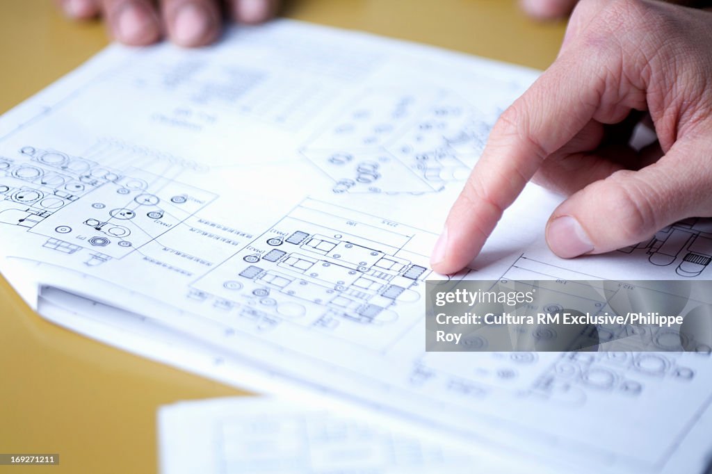 Close up of hands pointing to blueprints