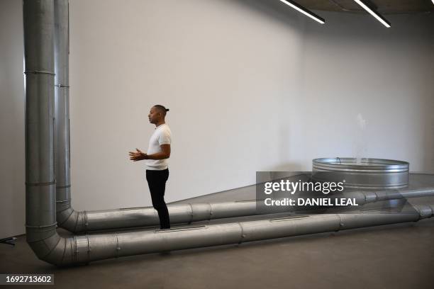 Journalist stands next to installations by artist Ghislaine Leung entitled 'Violets 2' and 'Fountains' during a photocall for the Turner Prize 2023...