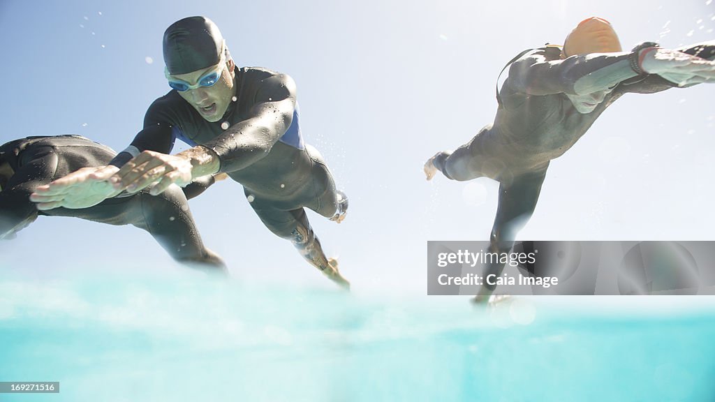 Triathletes en wetsuits corriendo al mar