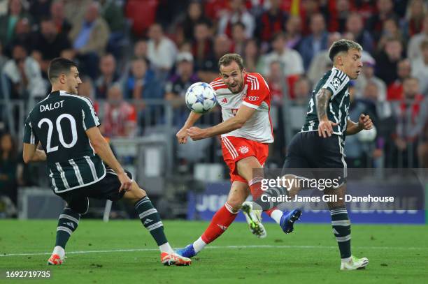 Harry Kane of FC Bayern München shoots past Diogo Dalot and Lisandro Martinez of Manchester United during the UEFA Champions League match between FC...