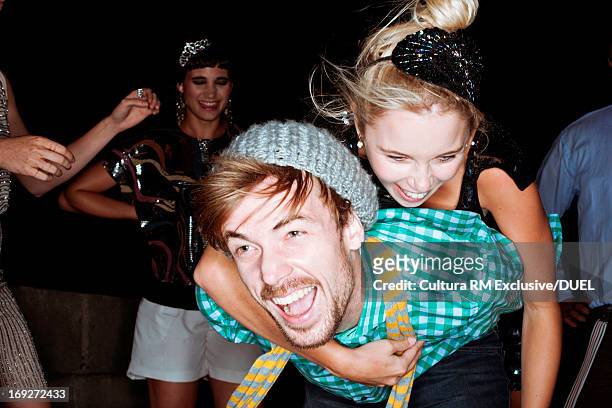 young friends giving piggybacks at party - glamour couple stock pictures, royalty-free photos & images