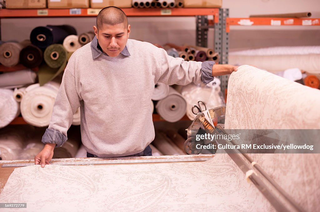 Textile factory worker measuring roll of fabric