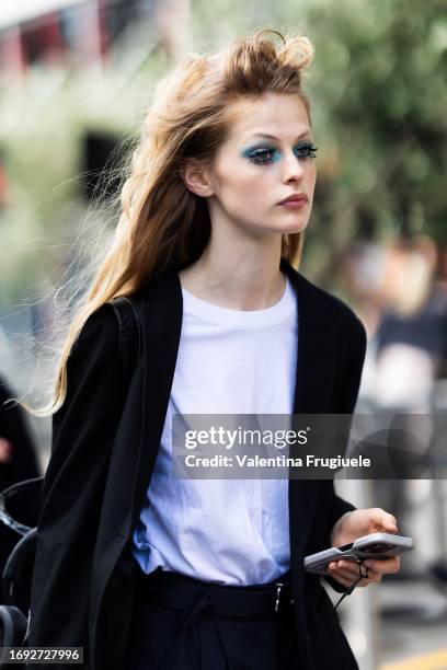 Guest is seen wearing bright blue eyeshadow, a white t-shirt, a black blazer, black trousers and a black bag outside Antonio Marras show during the...