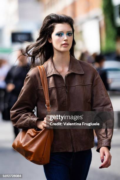 Guest is seen wearing bright blue eyeshadow, a brown leather jacket, an orange leather bag and blue jeans outside Antonio Marras show during the...
