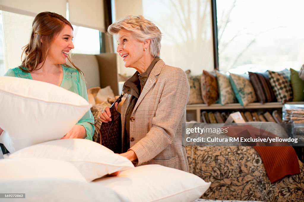 Senior woman choosing bedding in fabric shop with shop assistant