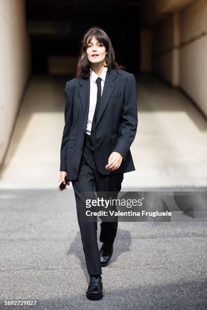 Ginevra Ferro is seen wearing a white shirt, a black tie, black leather loafers and a blue striped suit outsideAntonio Marras show during the Milan...