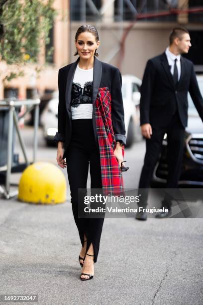 Olivia Palermo is seen wearing black, shiny leather heels, black high-waist trousers, a white t-shirt, a black lace bra and a black oversized blazer...