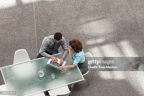 businessman and businesswoman sharing laptop at table - 2 ladies table computer stockfoto's en -beelden