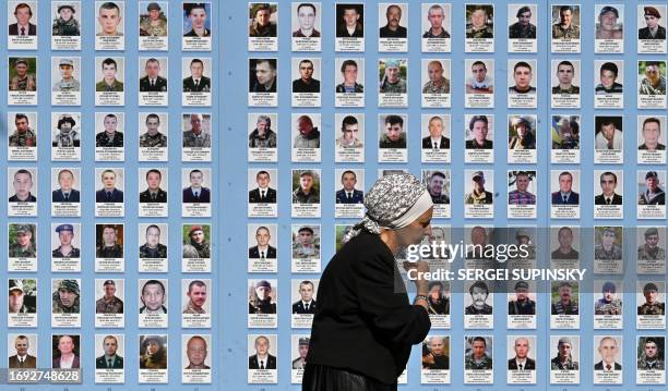 An elderly woman crosses herself as she walks past the Memory Wall of Fallen Defenders of Ukraine in the Russian-Ukrainian War in Kyiv on September...