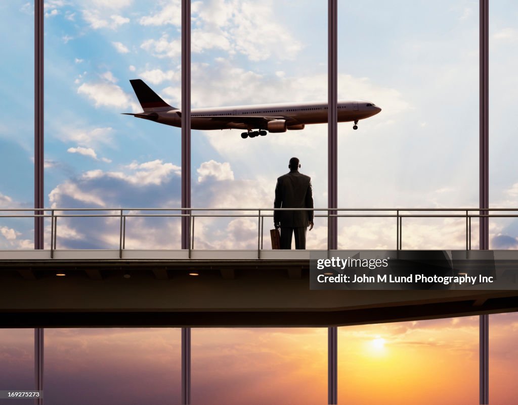 African American businessman watching plane in sky