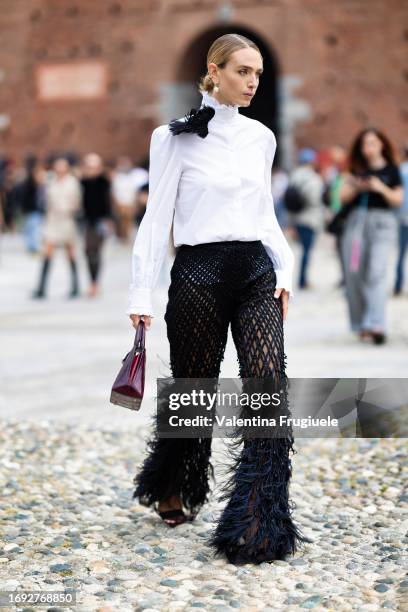 Guest is seen wearing fishnet pants with feathers and beads, a white high collar shirt and purple bag outside the Alberta Ferretti show during Milan...