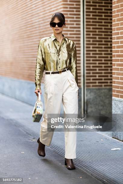 Guest is seen wearing a gold shiny cargo shirt, white pants and Fendi baguette outside the Fendi show during Milan Fashion Week Womenswear...