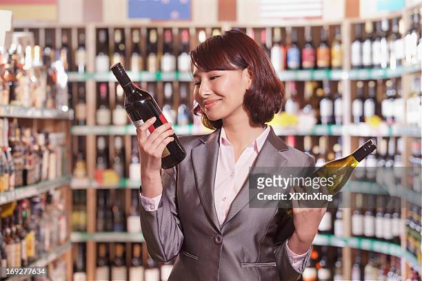 mid adult woman choosing wine in a liquor store - choosing wine stock pictures, royalty-free photos & images