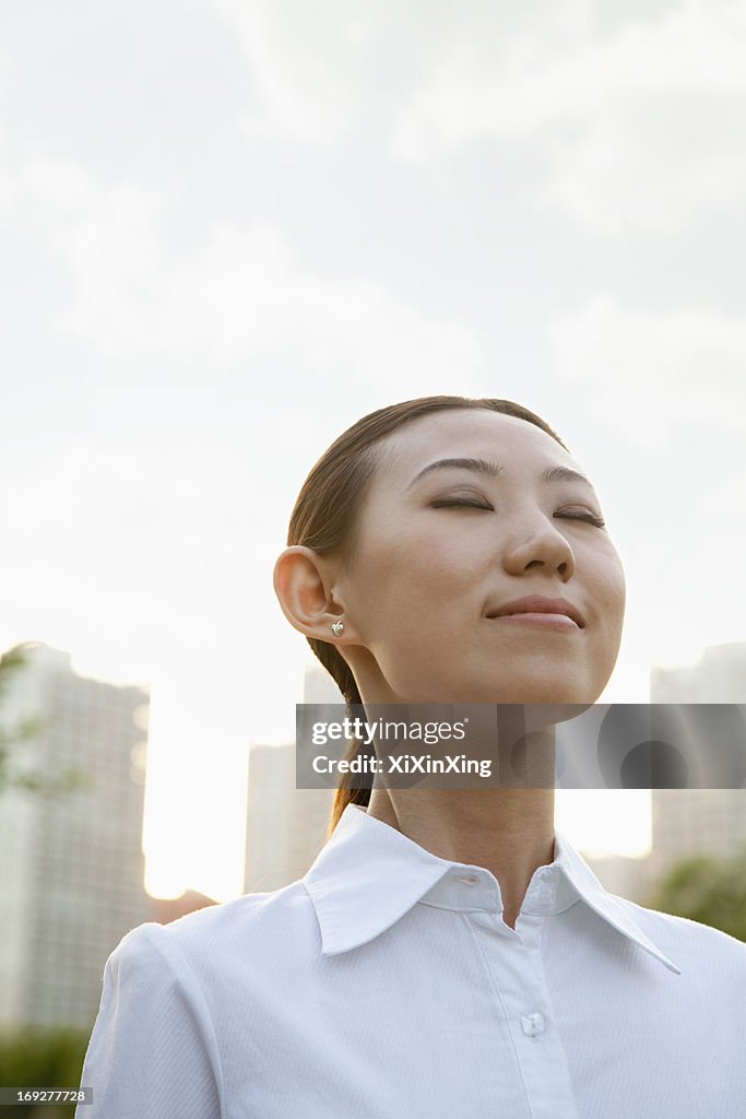 Portrait of smiling young woman outside, eyes closed