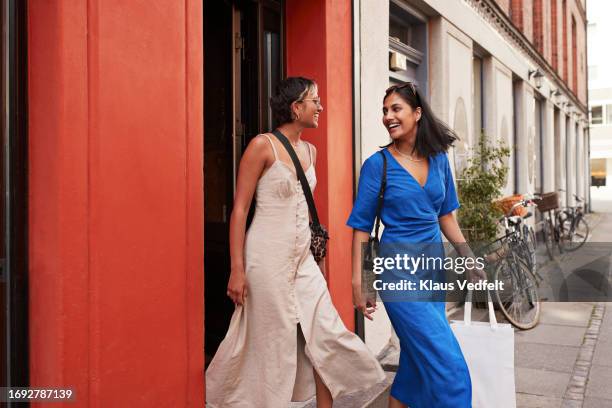 happy female friends walking out of store - happy customer leaving store stock pictures, royalty-free photos & images