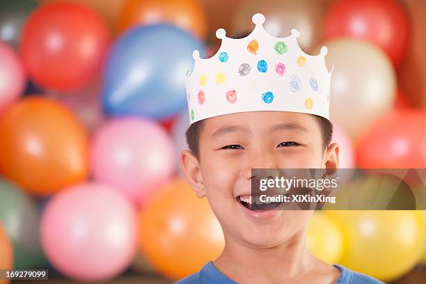 birthday boy wearing a crown in front of balloons - paper crown stock pictures, royalty-free photos & images