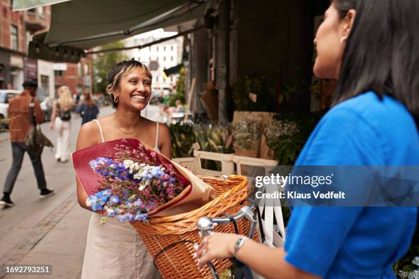 young woman with flowers in wicker bicycle basket talking to friend - hair colour streaks stock pictures, royalty-free photos & images
