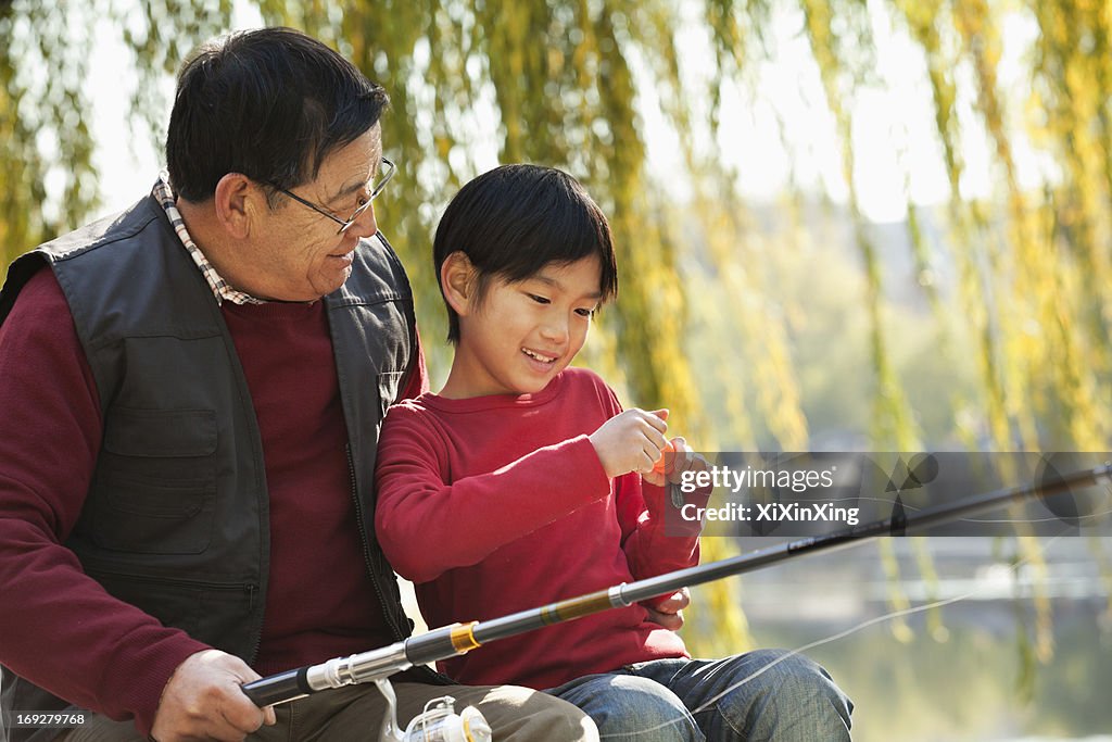 Grandfather and grandson putting lure on fishing line