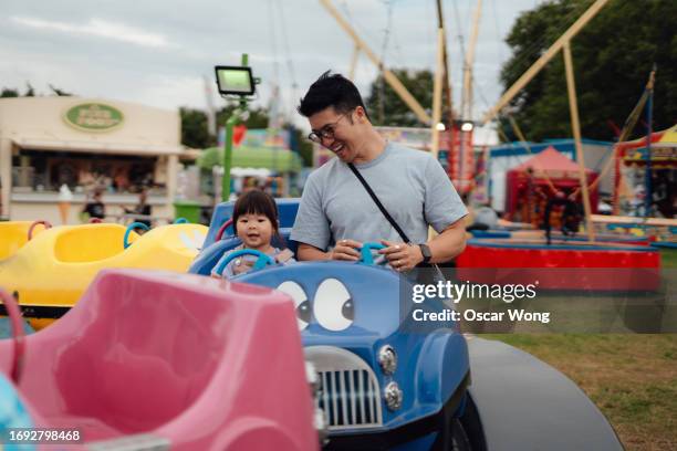 cheerful young asian father and daughter on carousel car ride at carnival - genderblend stock pictures, royalty-free photos & images