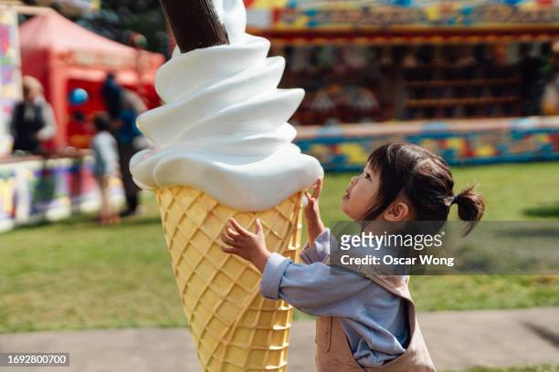cute asian toddler with giant ice-cream cone at the carnival - dream big foto e immagini stock