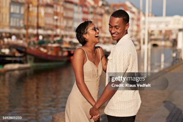 cheerful young man and woman holding hands - copenhagen nyhavn stock pictures, royalty-free photos & images