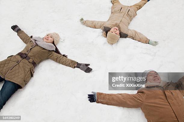 family laying in snow making snow angels - chinese father and son snow stock pictures, royalty-free photos & images