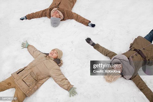 family laying in snow making snow angels - chinese father and son snow stock pictures, royalty-free photos & images