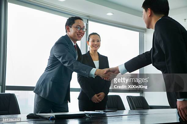 businessmen greeting each other with a handshake - asian shaking hands stockfoto's en -beelden