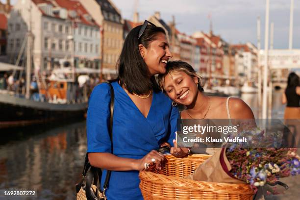 smiling young woman leaning on female friend - copenhagen nyhavn stock pictures, royalty-free photos & images
