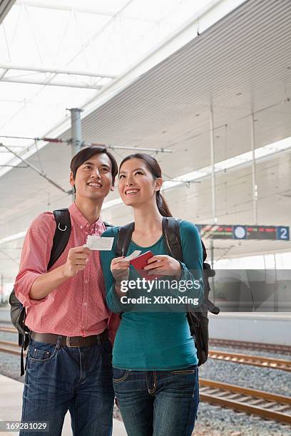 young couple checking the train schedule - dual railway stock pictures, royalty-free photos & images