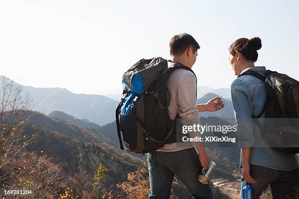 young couple hiking and looking at the compass - holiday hours stock-fotos und bilder
